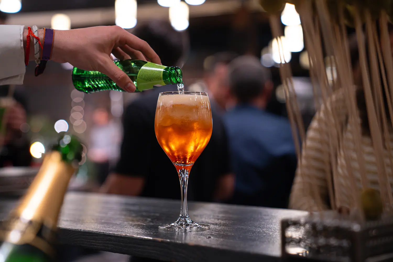 Ein professioneller Barkeeper gießt auf einer Party in festlicher Atmosphäre einen Drink ins Glas